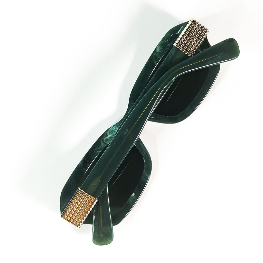 vue diagonale d’une monture Lanvin vert marbré, verres teintés verts, charnière recouverte d’un motif de chaîne dorée, fond blanc