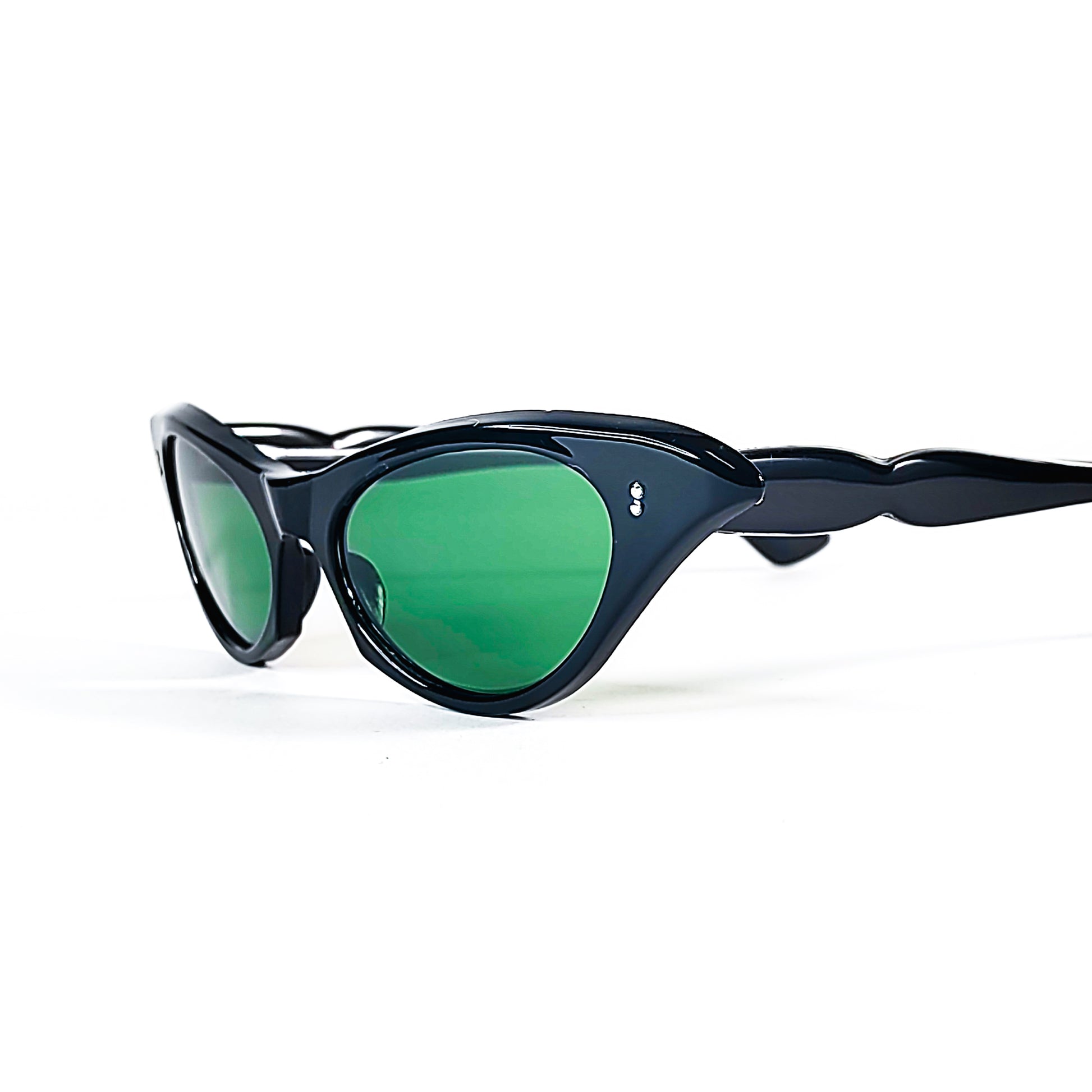 Vue de trois quarts sur des lunettes de soleil œil-de-chat vintage noires à verres verts et branches sculptées